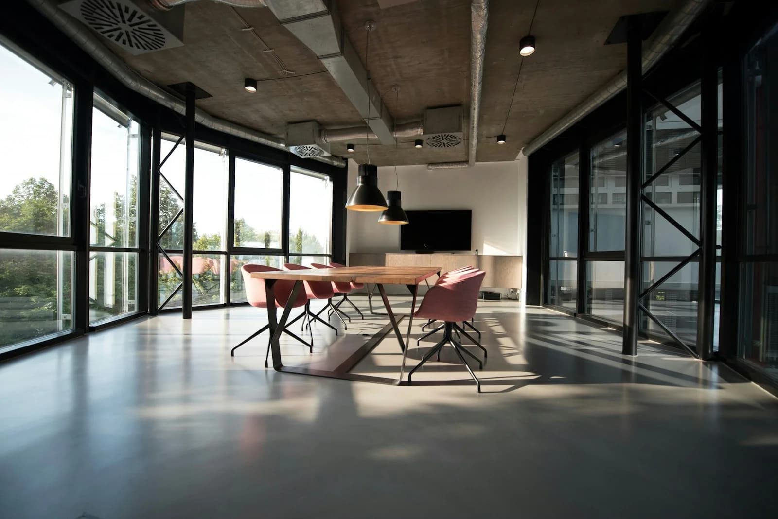 Contemporary office meeting space with full-height glazing, a timber table and upholstered chairs; workplace inspiration